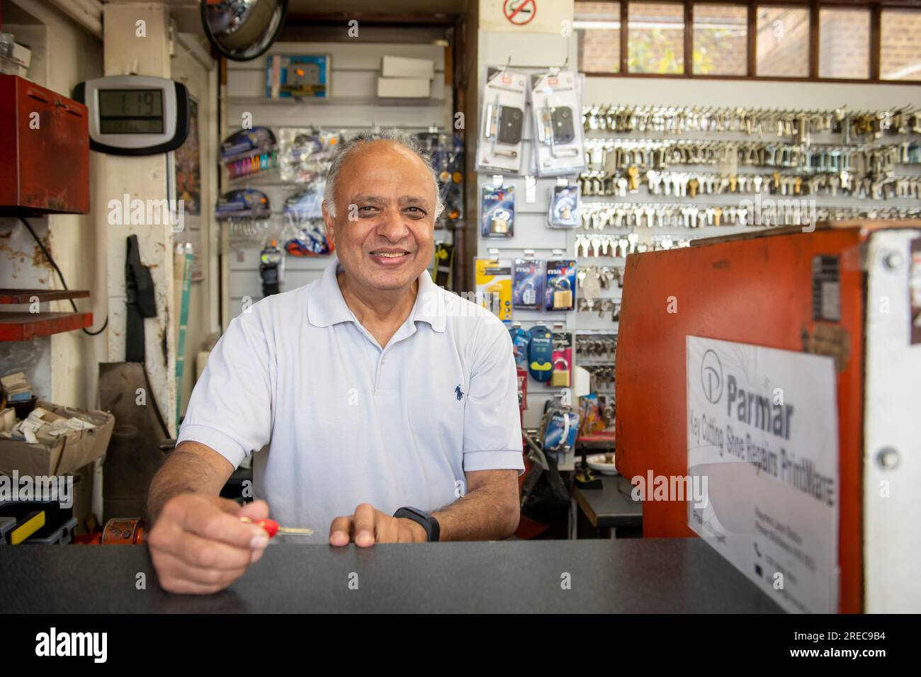 Der Ladenbesitzer mr. Parmar in seinem kleinen Schlüsselschneider- und cobler-Laden in der Rayners Lane in Harrow North West London. Der Laden ist am Bahnhof. Stockfoto