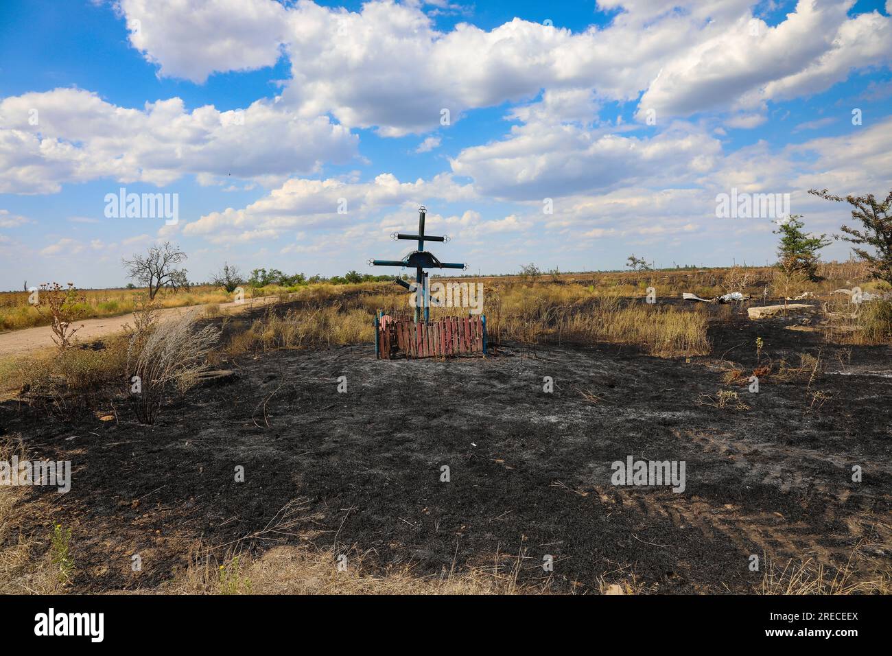 BLAHODATNE, UKRAINE - 19. JULI 2023 - Ein Grabkreuz ist umgeben von ausgebranntem Gras im Dorf Blahodatne, Mykolaiv Region, Süd-Ukraine, Wai Stockfoto