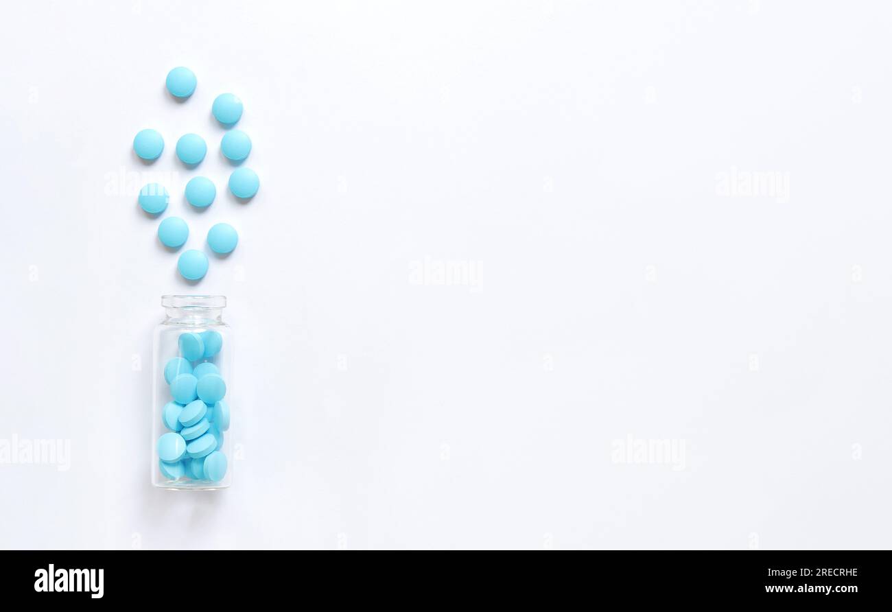 Blaue Pillen aus einer Glasflasche auf weißem Hintergrund. Vitaminkomplex, Kopierraum. Gesundheitsfürsorge, Schmerzmittel, Medikamentenpillen und Nahrungsergänzungsmittel Stockfoto