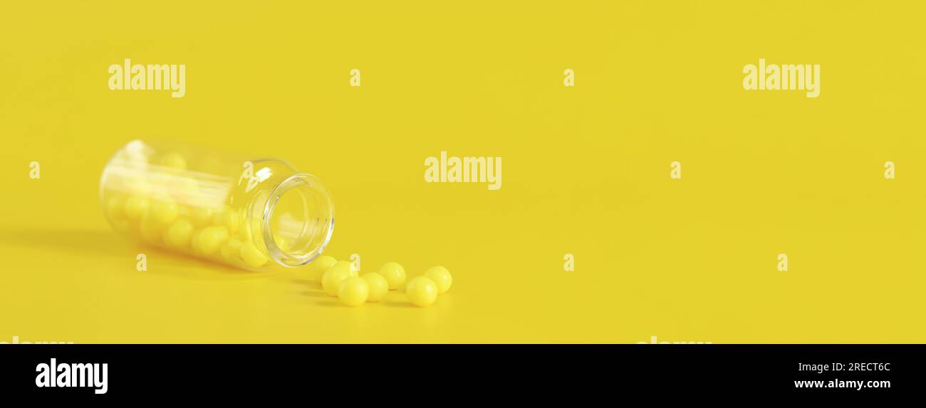 Gelbe Tabletten in einer Glasflasche, Ascorbinsäure. Die Vitamine C werden auf gelbem Hintergrund ausgeschüttet. Epidemie, Schmerzmittel, Medizin-Pillen und Gesundheitspflege Stockfoto