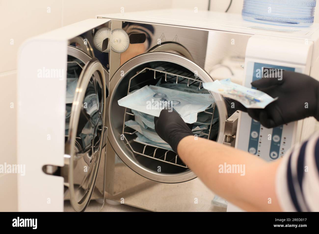 Hände in schwarzen Handschuhen, die ein medizinisches Instrument halten. Sterilisationsbox. Sterilisation von Instrumenten. Zahnarztwerkzeuge. Sterilisationsverfahren. Dampf-Autom Stockfoto