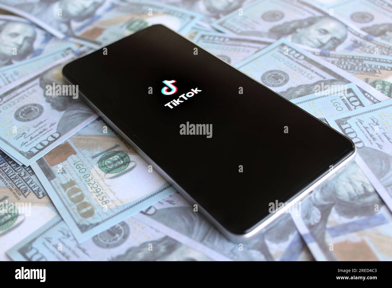 TikTok App-Logo auf Smartphone und Geld. Umsatz-, Geschäfts- und Gewinnkonzept Stockfoto