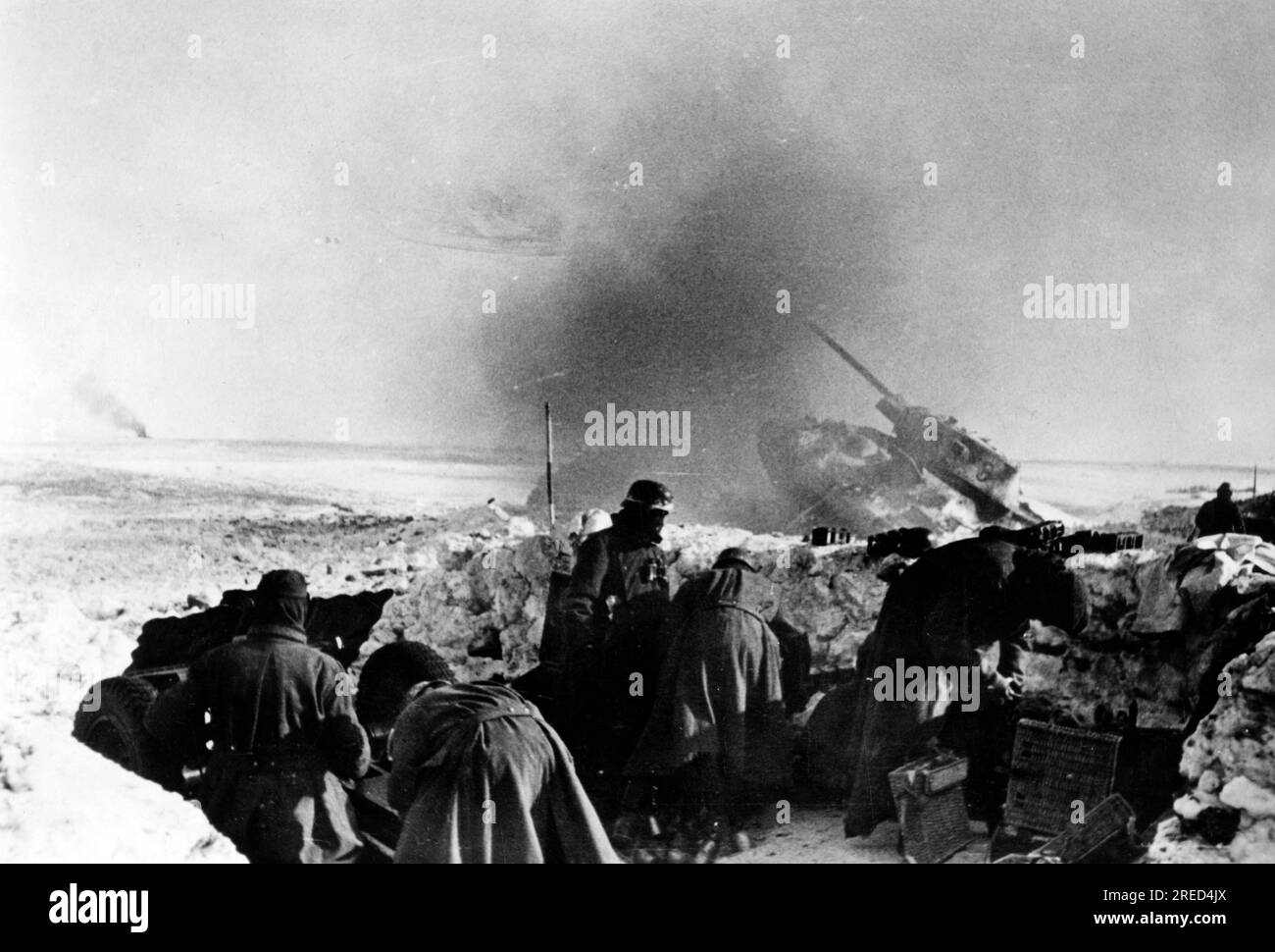 Deutsche Soldaten mit einer Infanteriewaffe an der Ostfront. Im Hintergrund wurde ein russischer T34-Panzer abgeschossen. Foto: Kraayvanger. [Maschinelle Übersetzung] Stockfoto