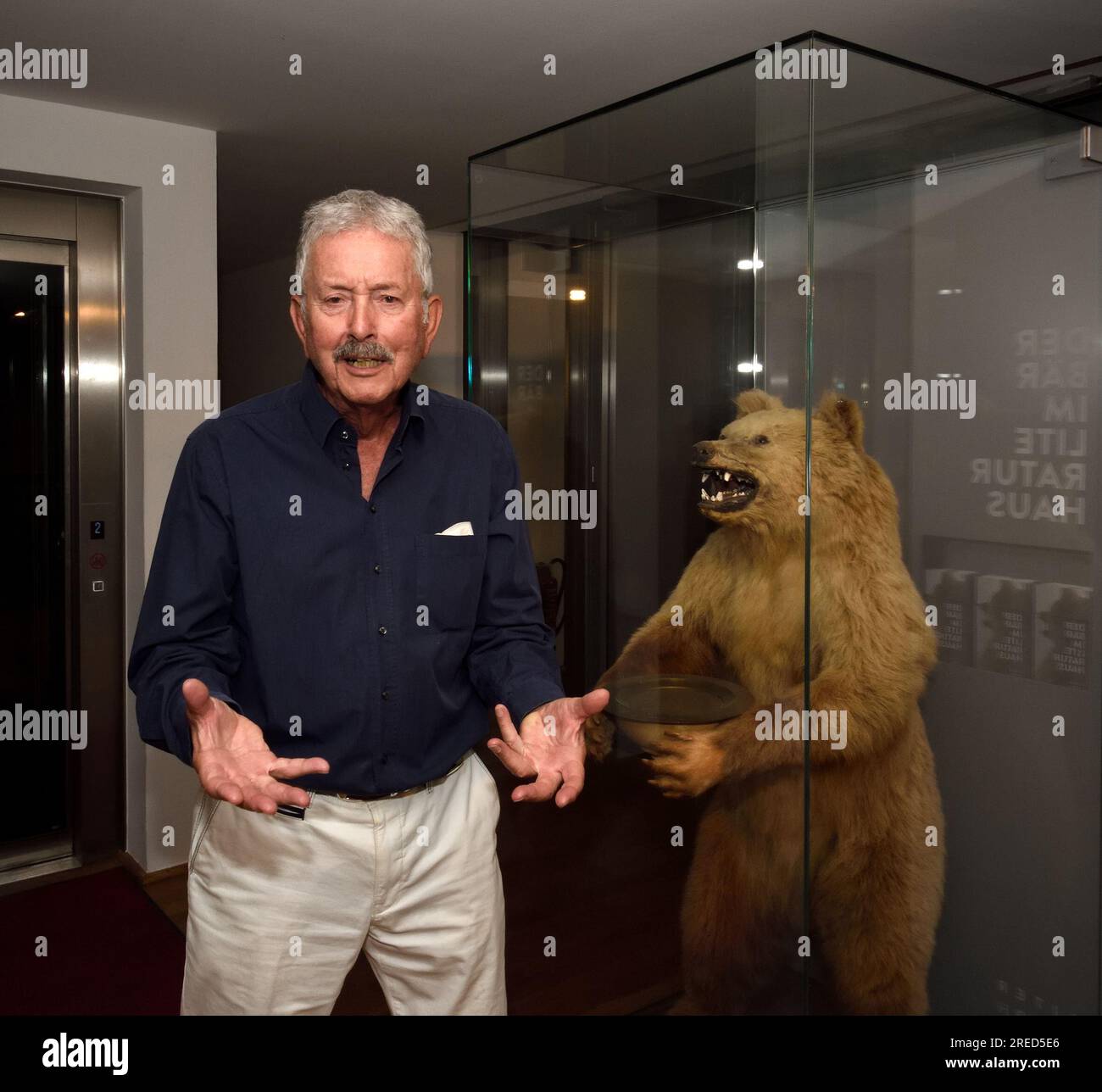 Theaterkritiker, Kulturredakteur und Radiomoderator Michael Skasa (B.1942) posiert vor dem Bären aus dem Haus von Thomas Mann im Münchner Literaturhaus. Juli 2022. [Maschinelle Übersetzung] Stockfoto