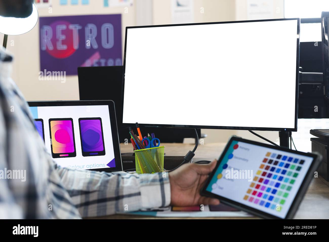 Mittelteil eines indischen männlichen Designers, der Tablet und Computer benutzt, mit Kopierplatz am Schreibtisch im Büro Stockfoto