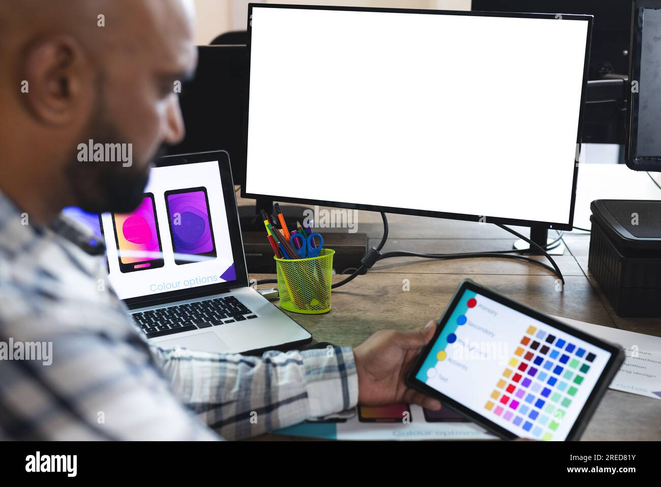 Indischer Designer, der Tablet und Computer mit Kopierbereich am Schreibtisch im Büro benutzt Stockfoto