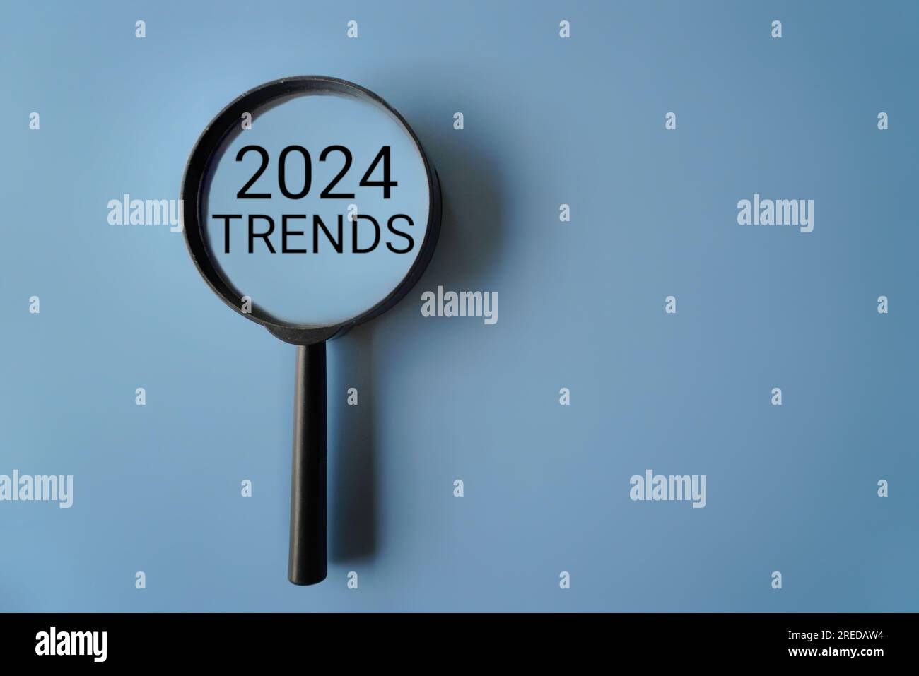 Vergrößerungsglas und Text 2024-TRENDS auf blauem Hintergrund mit Kopierbereich Stockfoto