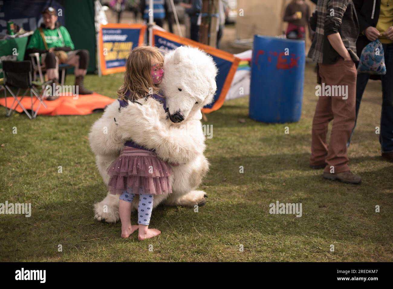 Eine Person in einem großen, flauschigen Eisbärkostüm umarmt ein kleines, gesichtsgemaltes Mädchen beim familienfreundlichen Roots Festival in Knockengorroch in Dumfries an Stockfoto