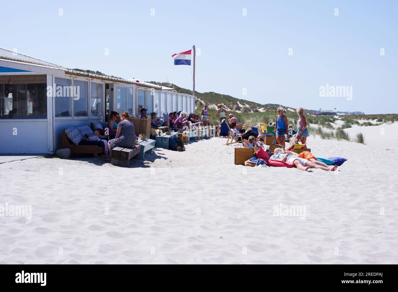 Terschelling, Niederlande - 16. Juni 2023: Gäste entspannen auf einer Terrasse vor einem Strandzelt im Sand Stockfoto