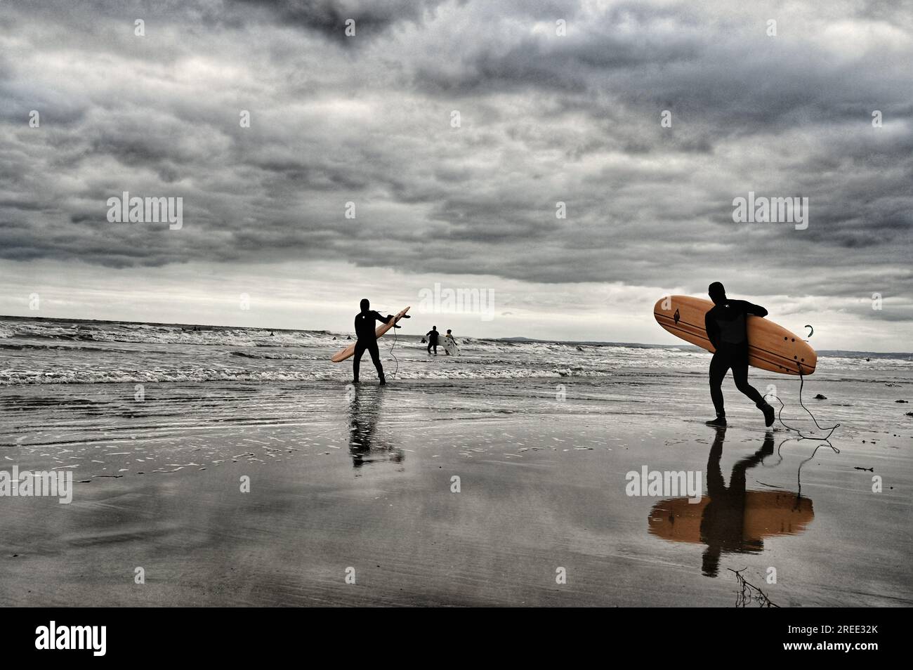 Surfer am Strand von Porthcawl mit einem dramatischen stürmischen Himmel Stockfoto