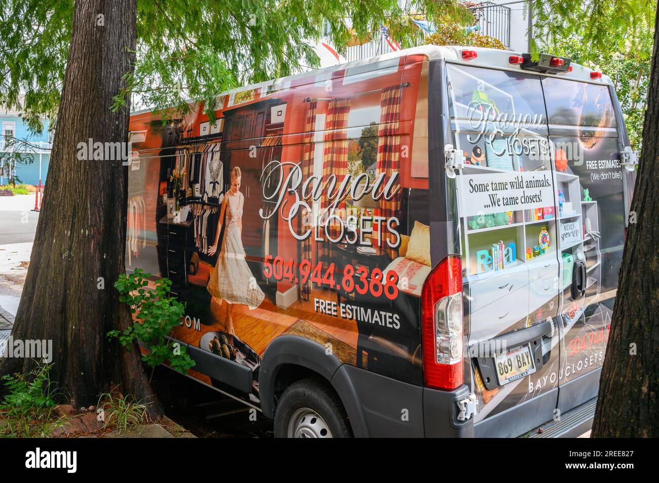 NEW ORLEANS, LA, USA - 23. JULI 2023: Bayou Closets (ein Schrankmacher- und Organisatorenunternehmen) Van parkt auf der Straße zwischen zwei Zypressen Stockfoto