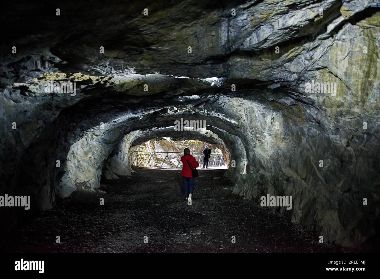 Eine Frau in einer roten Jacke geht tief in die Höhle mit Licht, Republik Karelien, Ruskeala Bergpark Stockfoto