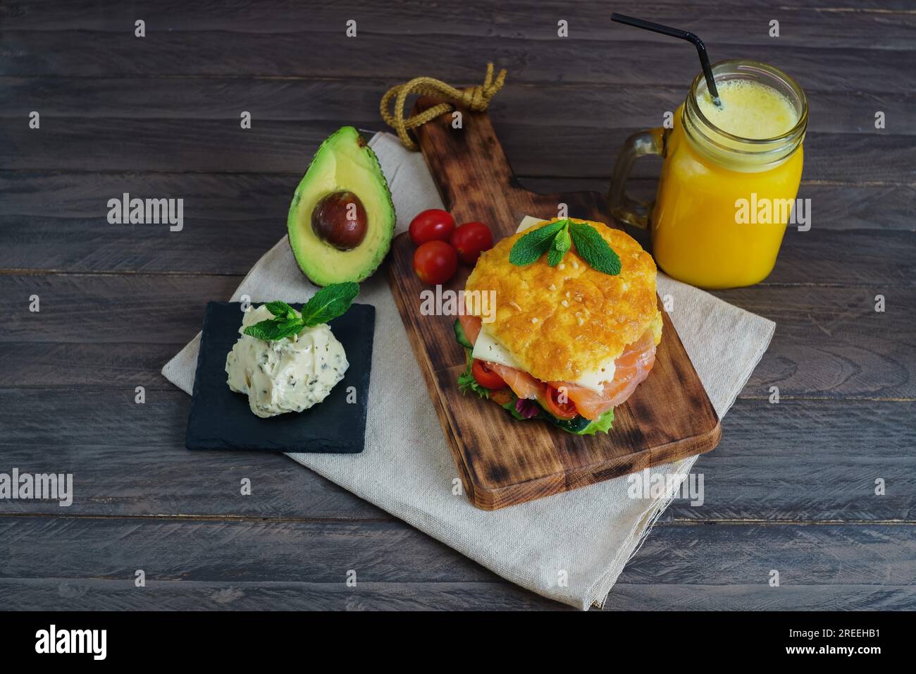 Ketogenes Diät-Sandwich mit Lachs, Käse, Tomaten und Gemüse das Brot wird glutenfrei mit Käse und Mandeln, Glas mit Orangensaft hergestellt Stockfoto