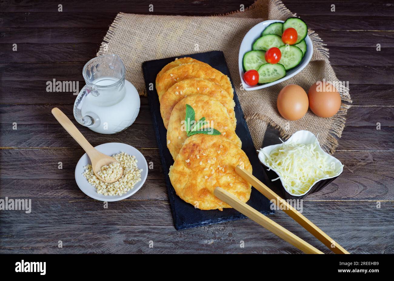 Keto-Brot mit Mandeln und Käse mit den Zutaten für die Zubereitung auf dem Holztisch Stockfoto