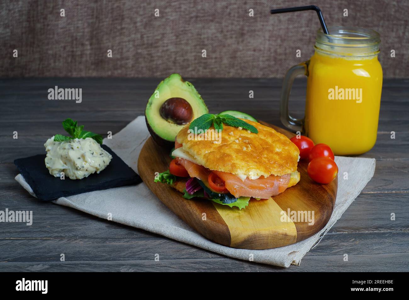 Ketogenes Diät-Sandwich mit Lachs, Käse, Tomaten und Gemüse das Brot wird glutenfrei mit Käse und Mandeln, Glas mit Orangensaft hergestellt Stockfoto