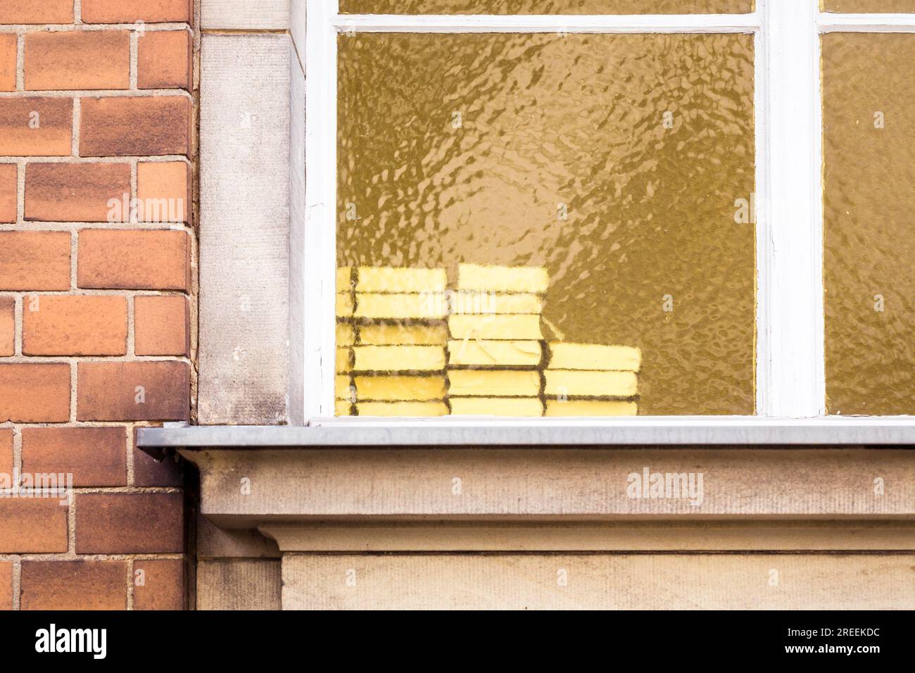 Ein Stapel Bücher hinter einem gelben Fenster Stockfoto