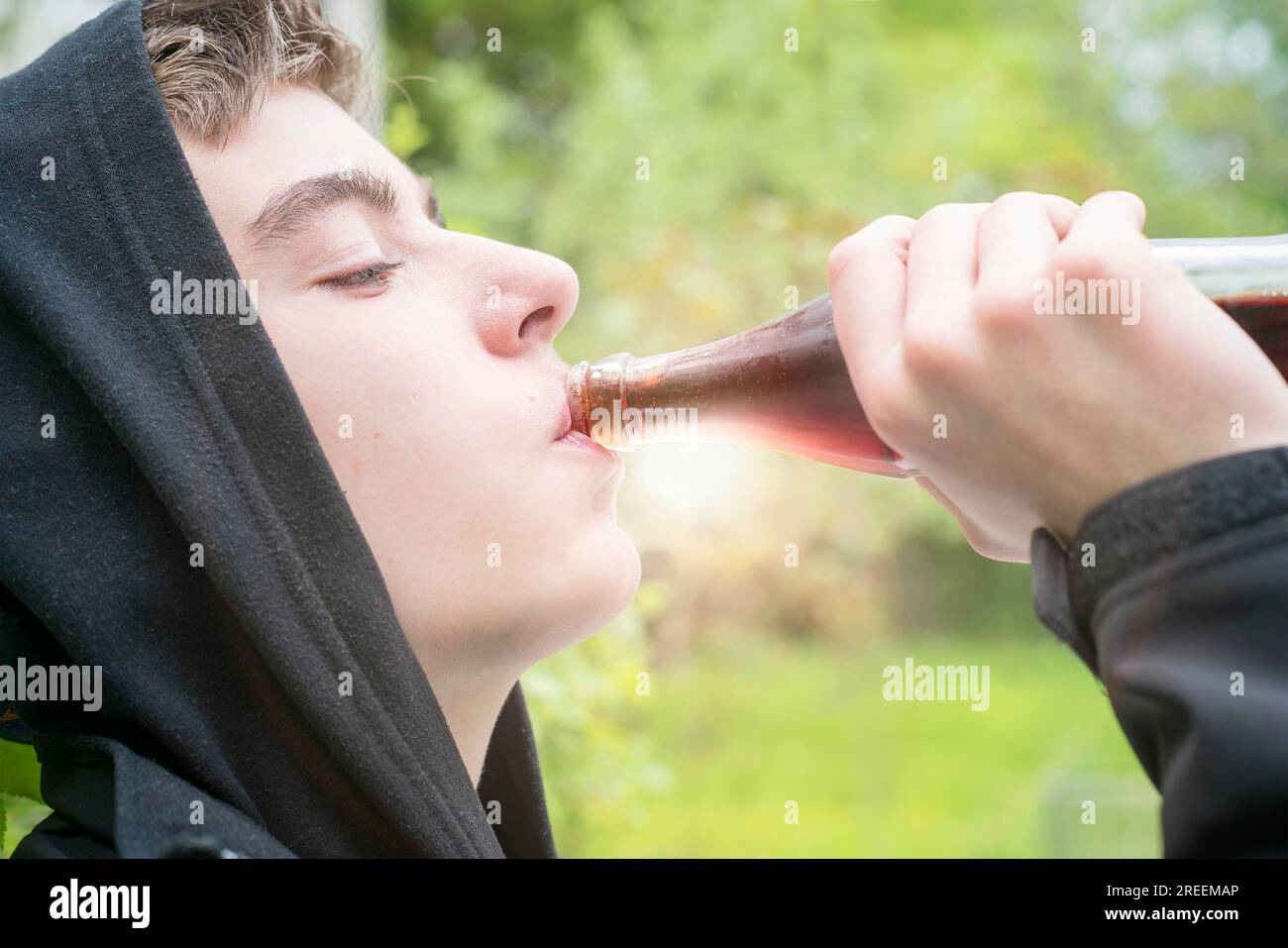 Junger Mann mit Kapuze, der eine Cola trinkt Stockfoto