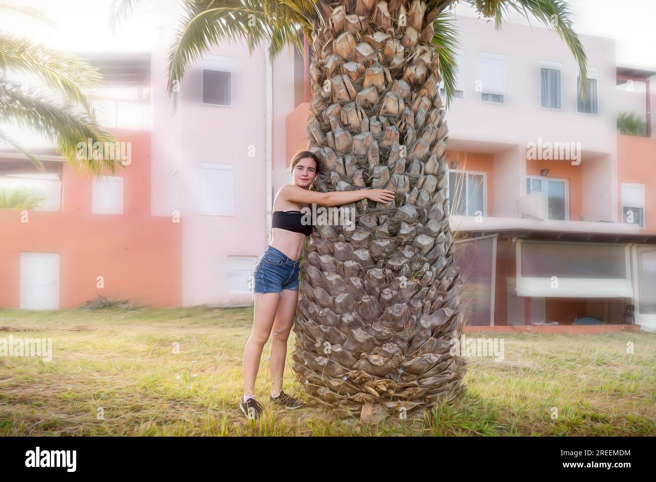 Junge lächelnde Frau umarmt eine Palme Stockfoto