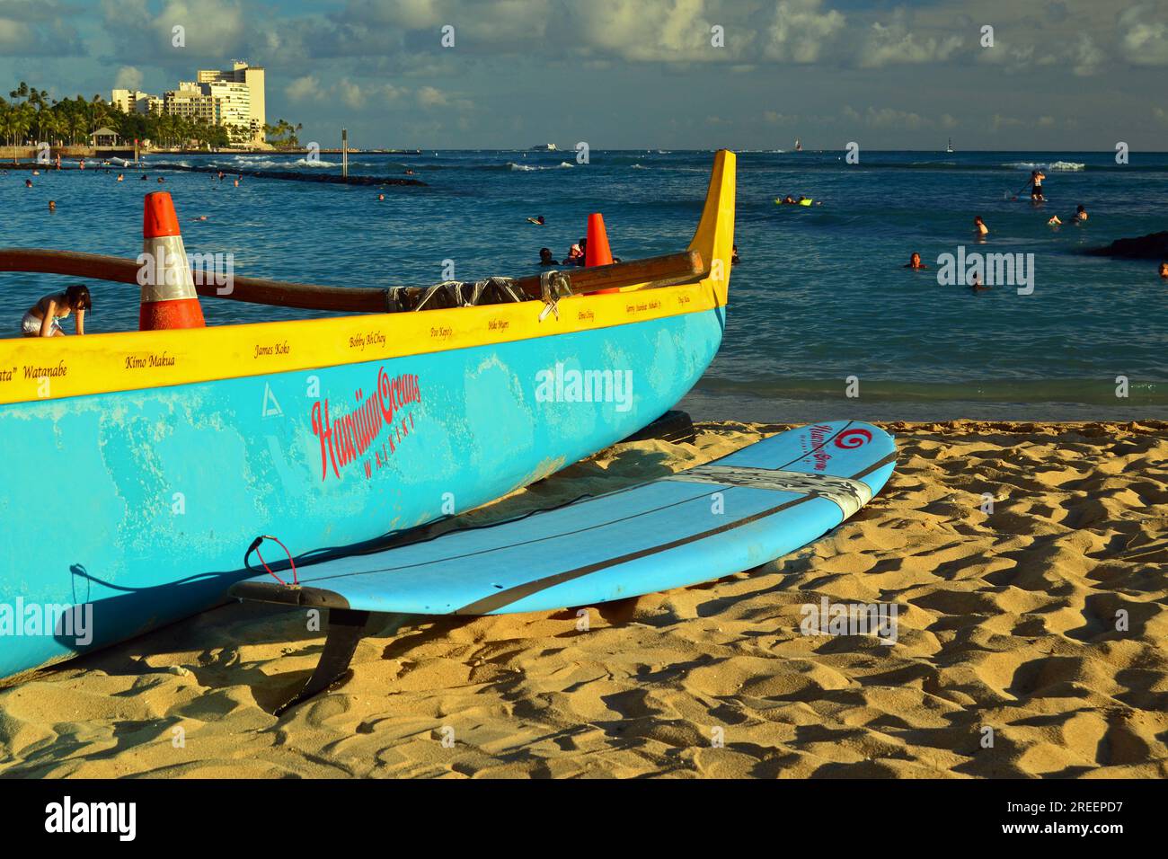 Ein Auslegerkanu und ein Surfbrett, zwei beliebte Transportmittel in Hawaii, ruhen sich auf dem Sand von Waikiki Beach aus Stockfoto