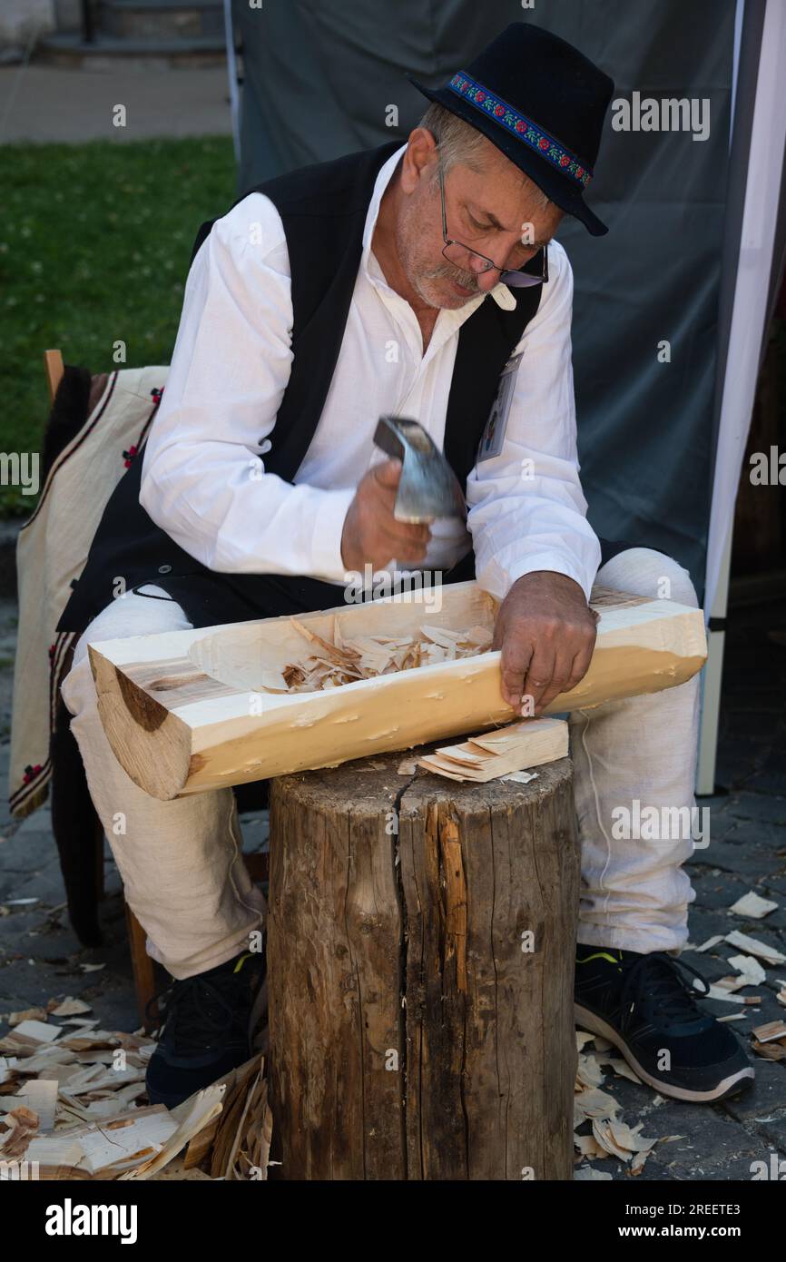 KEZMAROK, SLOWAKEI - 9. JULI 2023: Handwerker, die beim Europäischen Volks- und Handwerksfestival in Kezmarok, Slowakei, den Holztrog kreieren Stockfoto