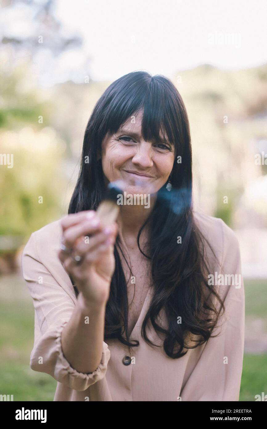 Eine Frau mit langen Haaren, die einen brennenden palo santo oder einen heiligen Baum hält Stockfoto