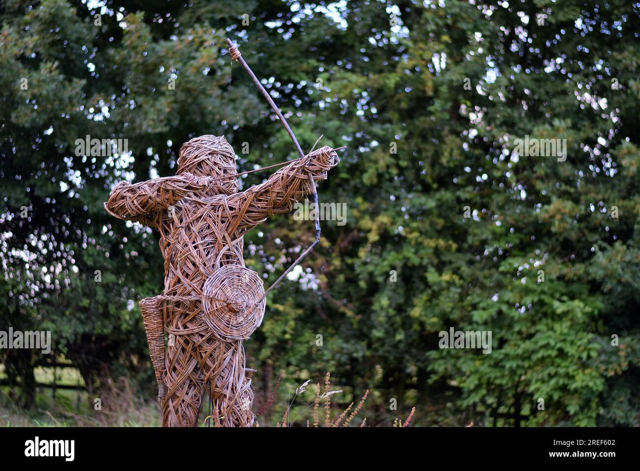 Eine große Holzbogenskulptur mit Pfeil und Bogen auf einem Hintergrund mit grünen Bäumen im Norden Englands. Stockfoto