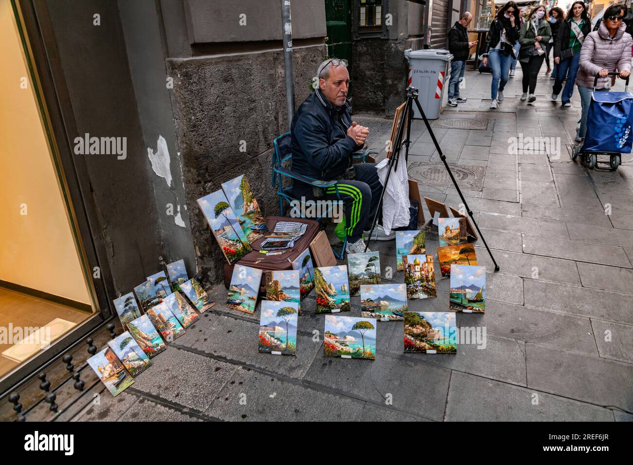 Neapel, Italien - 9. April 2022: Seniorenkünstler, der seine Gemälde auf einem Verkaufsstand in Neapel, Italien, verkauft. Stockfoto