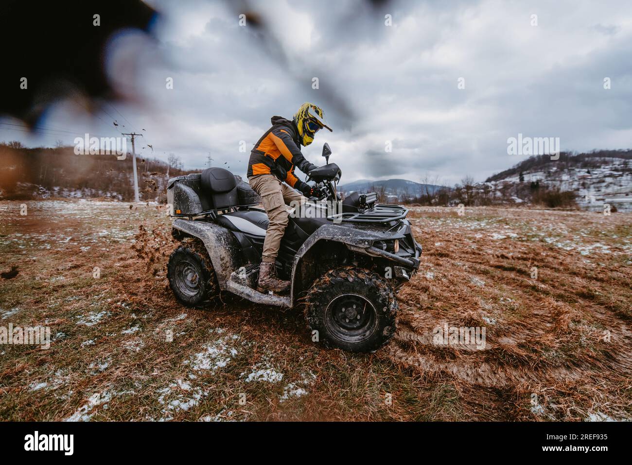 Ein Mann genießt furchtlos eine abenteuerliche Fahrt auf einem Quad durch gefährliches verschneites Gelände und nimmt den Nervenkitzel und die Aufregung des auf Stockfoto