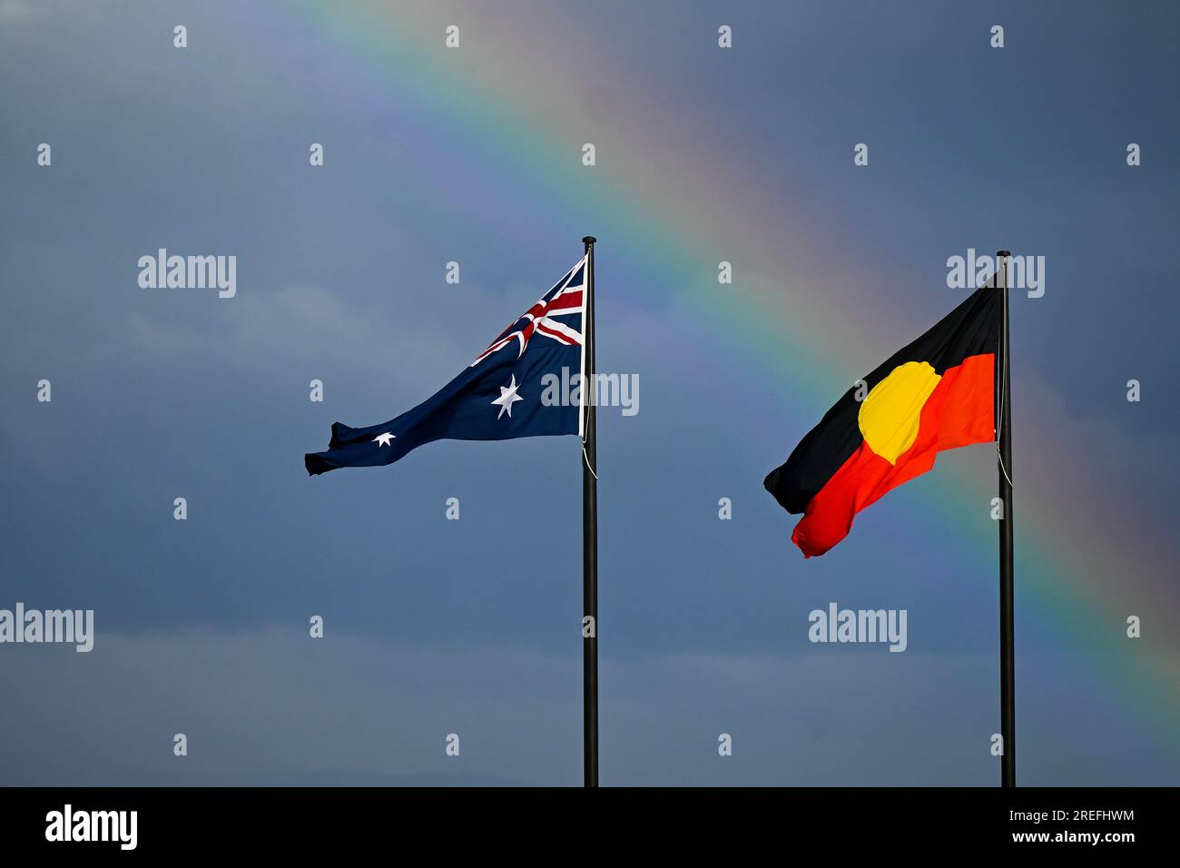 Canberra, Australien. 28. Juli 2023. Ein Regenbogen ist hinter der australischen Flagge und der indigenen Flagge in Canberra zu sehen, Freitag, den 28. Juli 2023. (AAP Image/Lukas Coch) KEIN ARCHIVIERUNGSGUTHABEN: Australian Associated Press/Alamy Live News Stockfoto