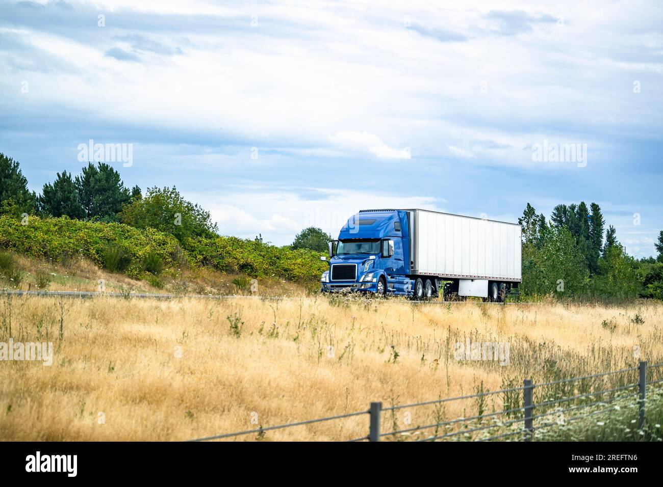 Großer Lkw-Lkw-Lkw-Traktor in Industriequalität, blau, mit hoher Fahrerkabine für Lkw-Fahrer, die gewerbliche Fracht in einem Auflieger für Trockentransporter transportieren Stockfoto
