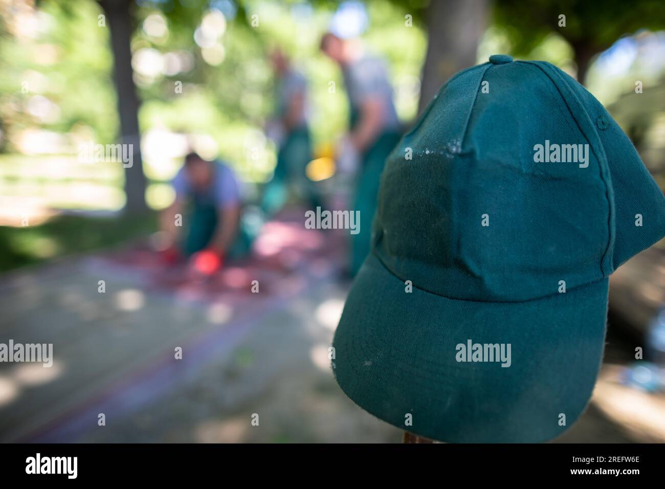 Die grüne Baseballmütze eines Bauarbeiters hängt an einem Holzhaken. Stockfoto