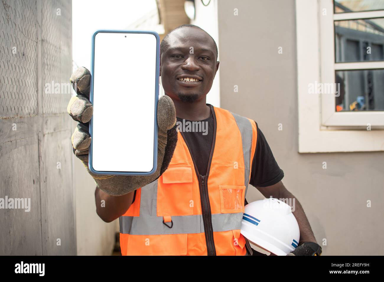 Ein afrikanischer Ingenieur, der seinen Telefonbildschirm zeigt Stockfoto