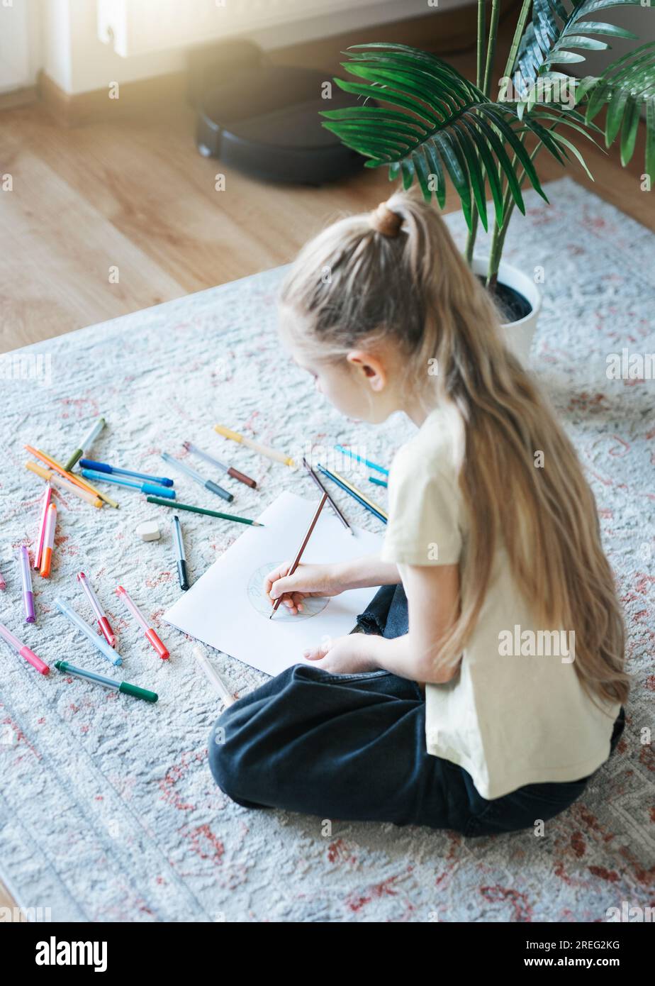 Kindermädchen malt zu Hause mit bunten Bleistiften. Ökologie-Konzept, Erde malen. Stockfoto