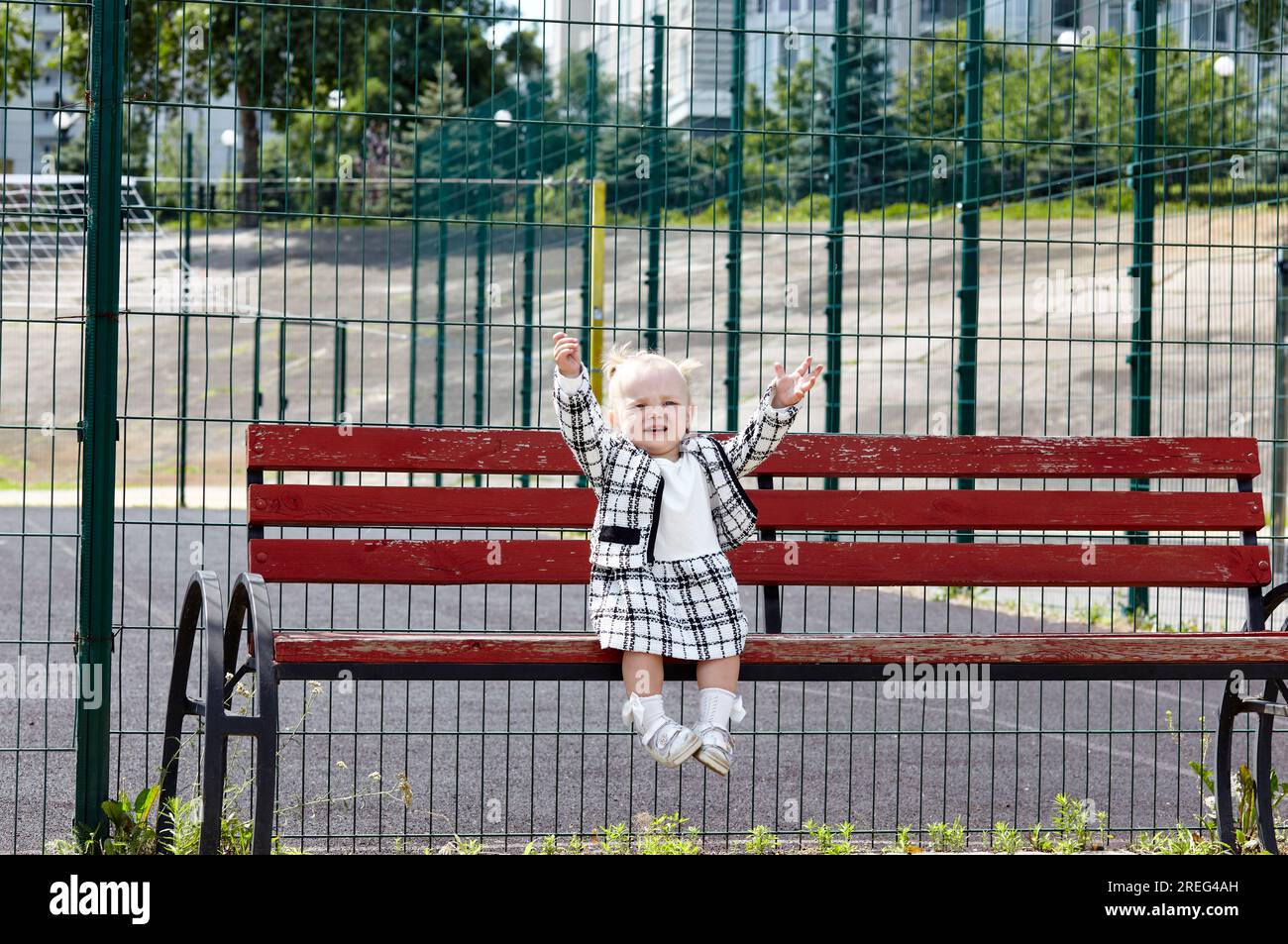 Trauriges kleines Mädchen, das auf einer Bank sitzt und auf mom wartet. Kinderverlust im Stadtpark Stockfoto