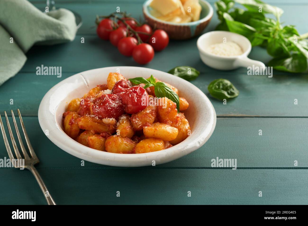 Kartoffelgnocchi. Traditionelle hausgemachte Kartoffelgnocchi mit Tomatensoße, Basilikum und Parmesan auf türkisfarbenem rustikalem Küchentisch. Traditi Stockfoto