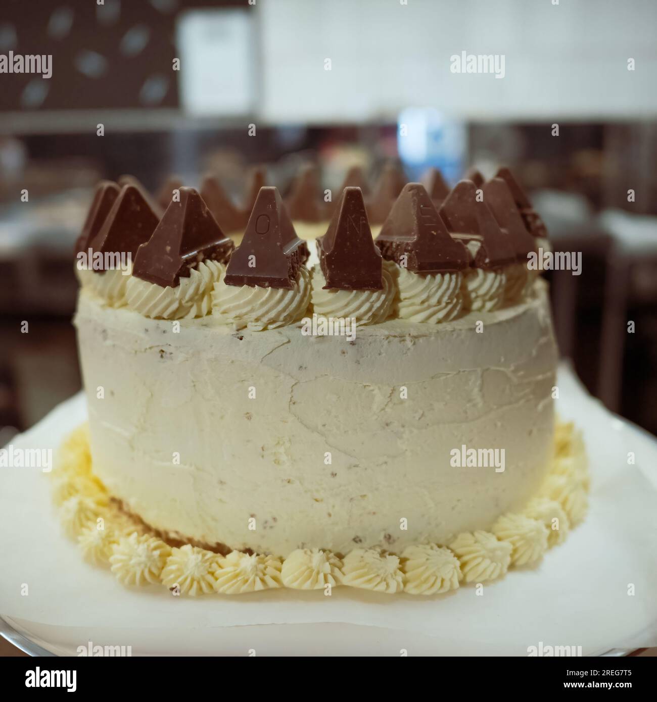 Weißer Schokoladenkuchen mit weißer Zuckerglasur und mit Schokoladenstücken und pipettierten Isomennestern gekrönt. Stockfoto