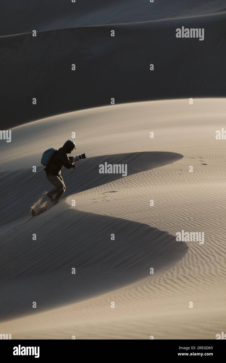 Ein Fotograf läuft eine Düne im großen Sanddünen-Nationalpark hinauf Stockfoto