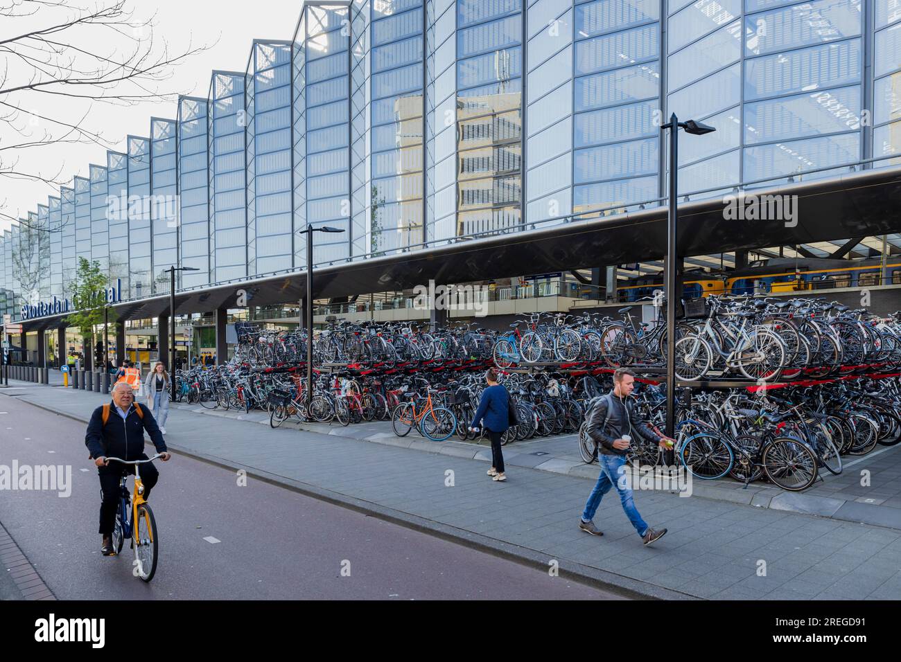 Rotterdam, Niederlande - 2022-04-21: Fahrradparkplatz hinter dem Rotterdamer Hauptbahnhof mit einem Gentleman, der auf einem OV-Fjets reitet Stockfoto