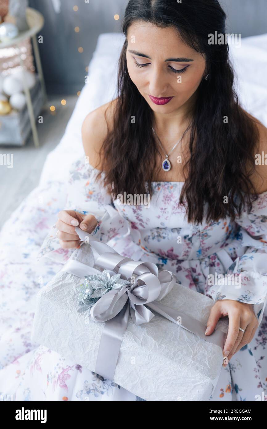 Ein Mädchen in einem weißen Kleid packt ein Geschenk aus Stockfoto