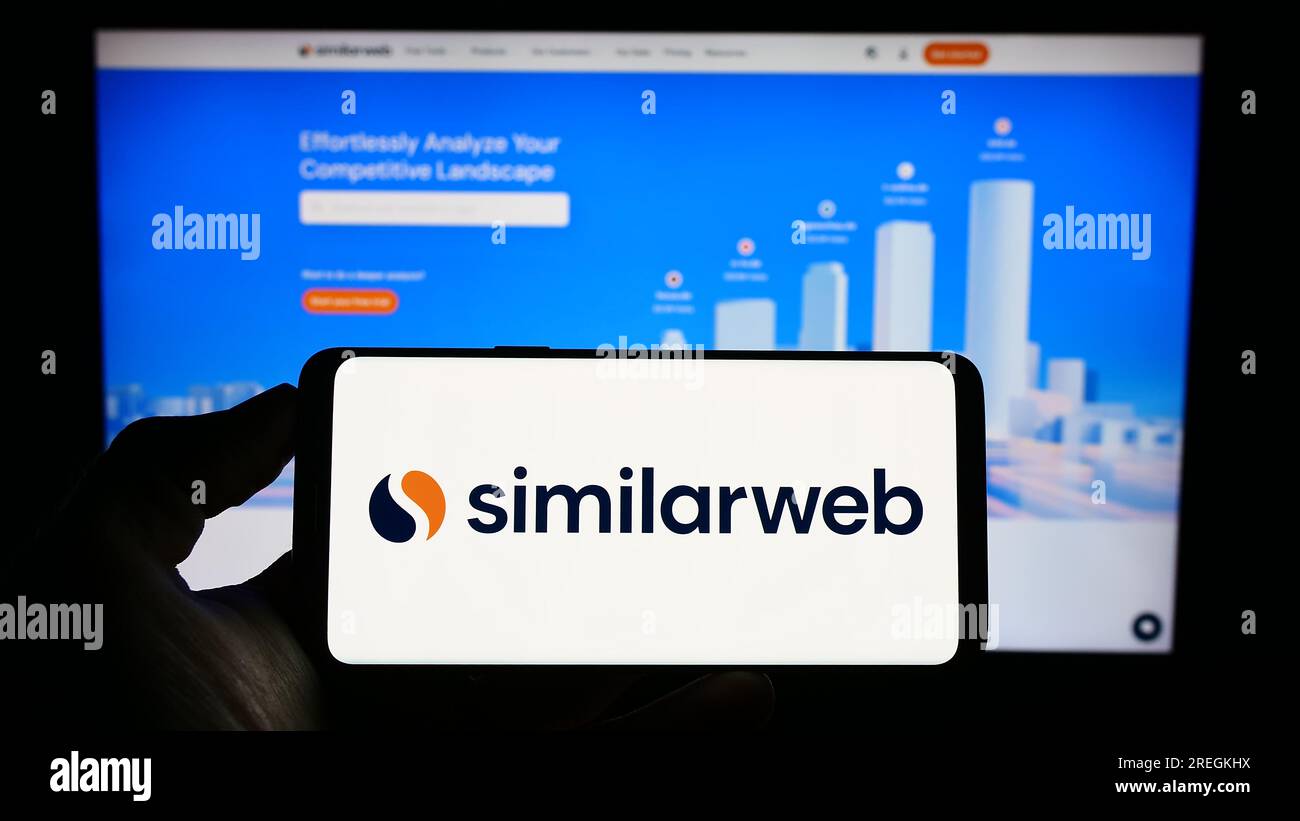 Person, die ein Mobiltelefon mit dem Logo des israelischen Webanalyseunternehmens SimilarWeb Ltd. Auf dem Bildschirm vor der Webseite hält. Konzentrieren Sie sich auf das Display des Telefons. Stockfoto