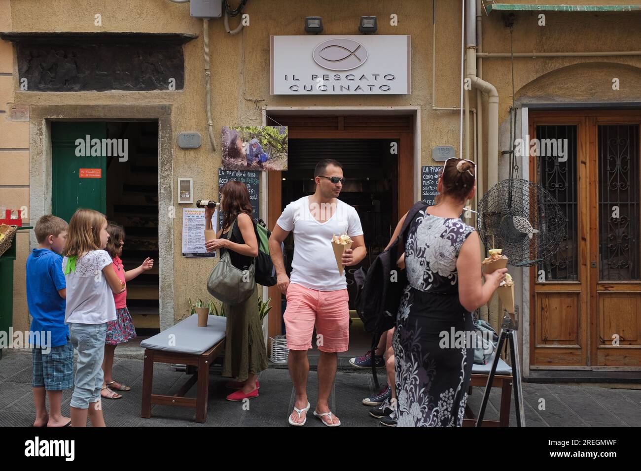 Cinque Terre, Italien: Touristen vor dem Il Pescato Cucinato, einem beliebten Restaurant in Riomaggiore, das gemischte gebratene Meeresfrüchte zum Mitnehmen anbietet. Stockfoto