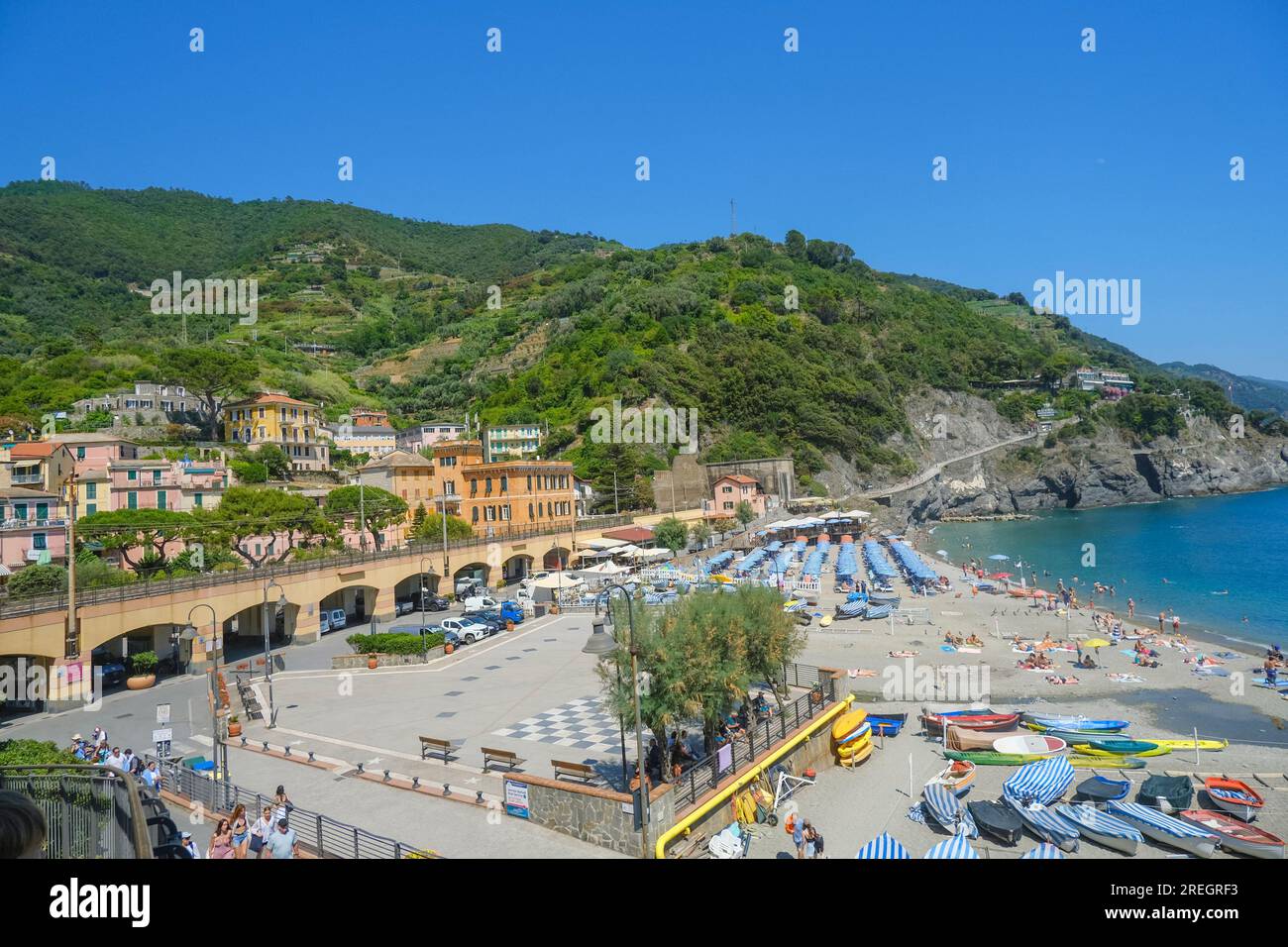 Luftaufnahme über Liegestühle und Sonnenschirme, Häuser und Bahnschienen in Monterosso, Cinque Terre, Ligurien, Italien, Italienische Riviera Stockfoto