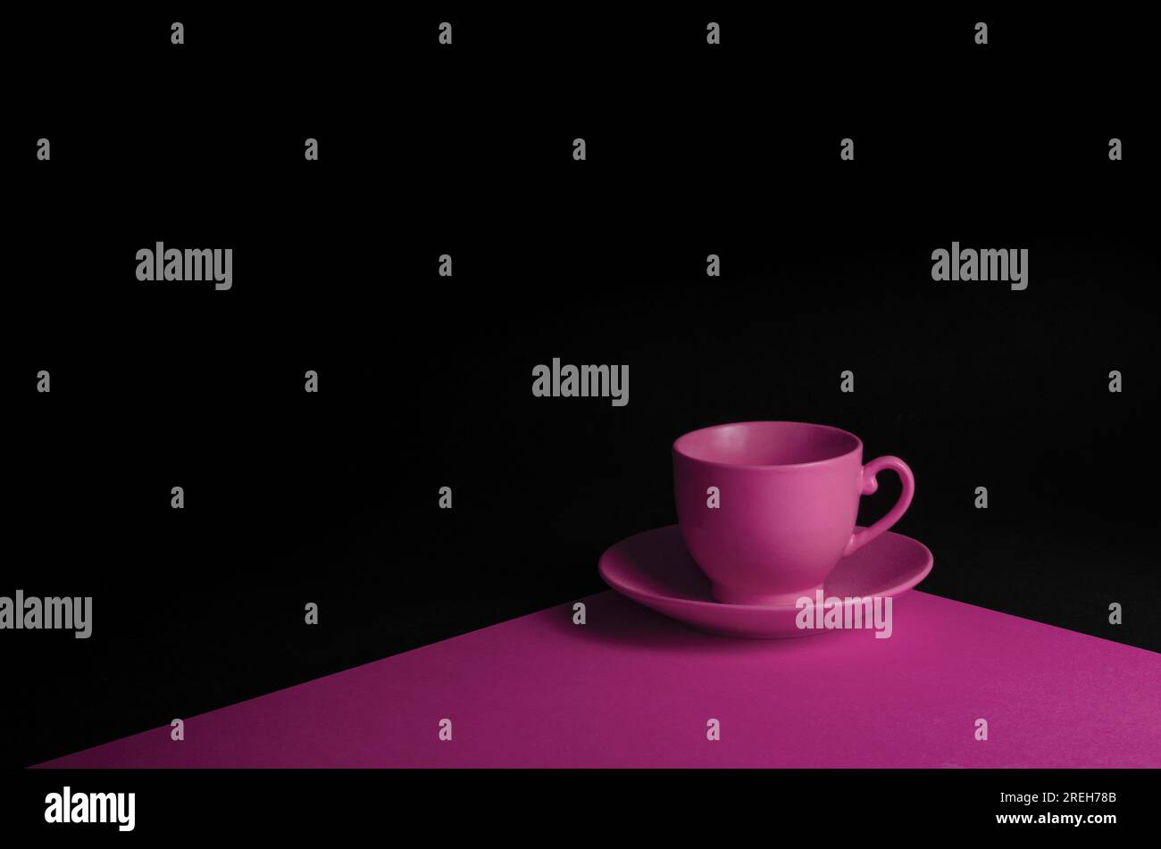 Eine Nahansicht einer weißen Kaffeetasse, Untertasse und eines Löffels, die auf einer rosa Oberfläche ruhen Stockfoto