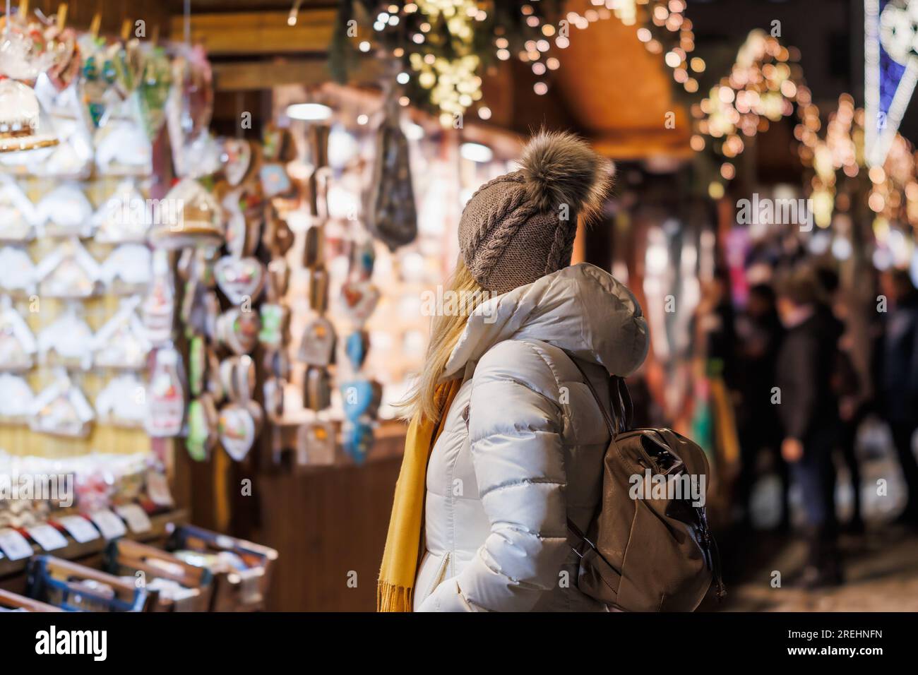 Eine Frau mit Strickmütze, die auf dem weihnachtsmarkt nach Souvenirs sucht. Weibliche Touristen genießen Winterurlaub in der Stadt Stockfoto