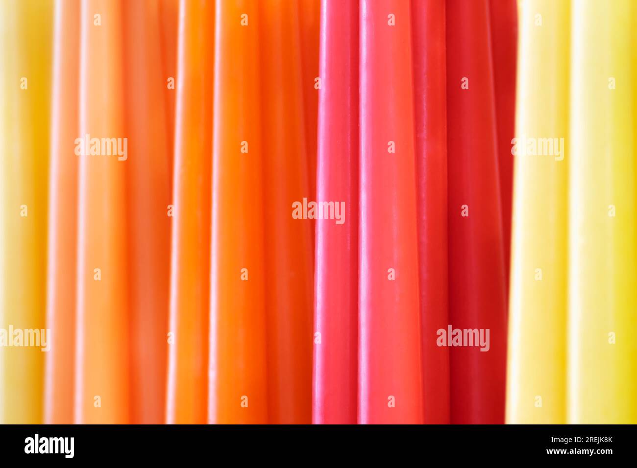Große Gruppe von bunten Wachskerzen, abstrakte parallele Linien, lebendige, warme Farben auf dem Hintergrund Stockfoto