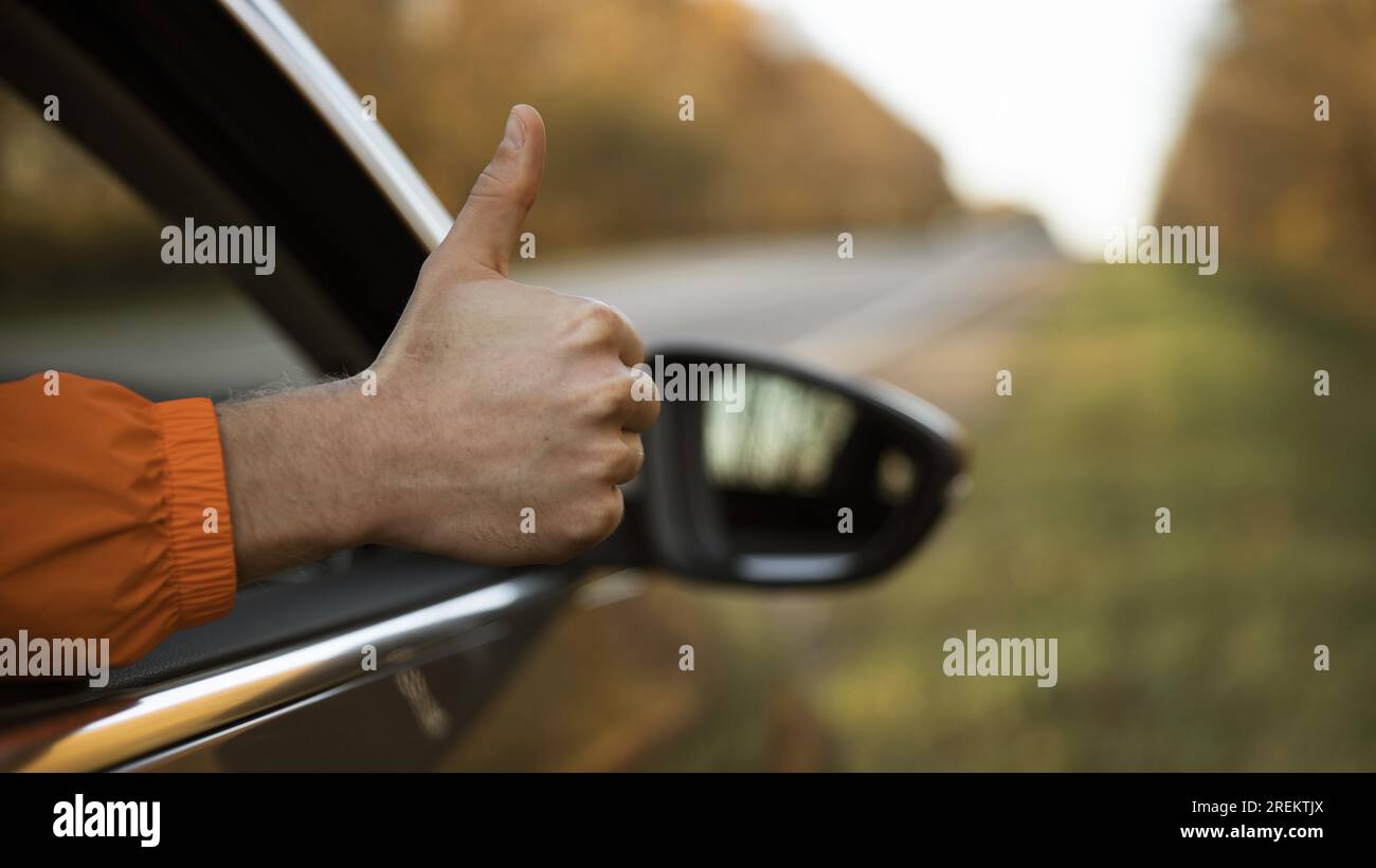 Ein Mann, der während einer Autofahrt Daumen nach oben drückt. Auflösung und hochwertige Fotos Stockfoto