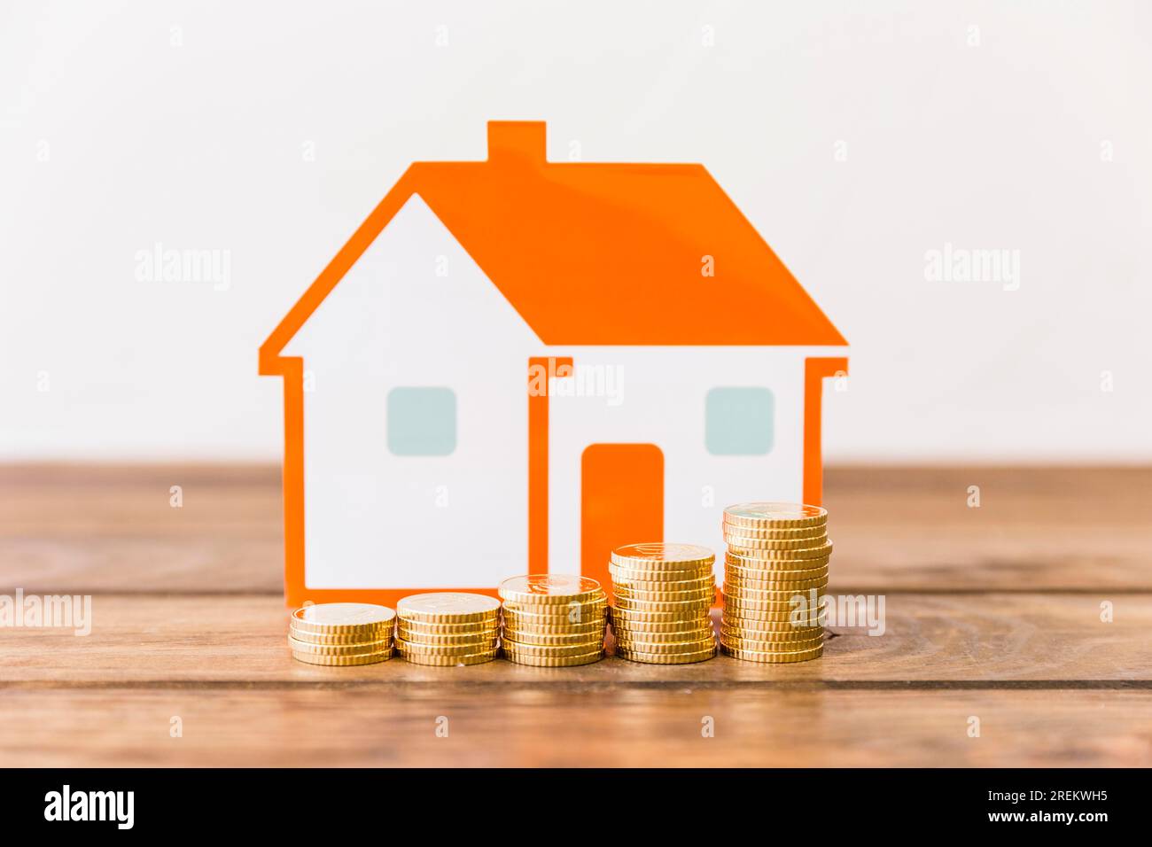 Nahaufnahme zunehmend gestapelte Münzen Hausmodell Holzschreibtisch. Schönes Foto Stockfoto