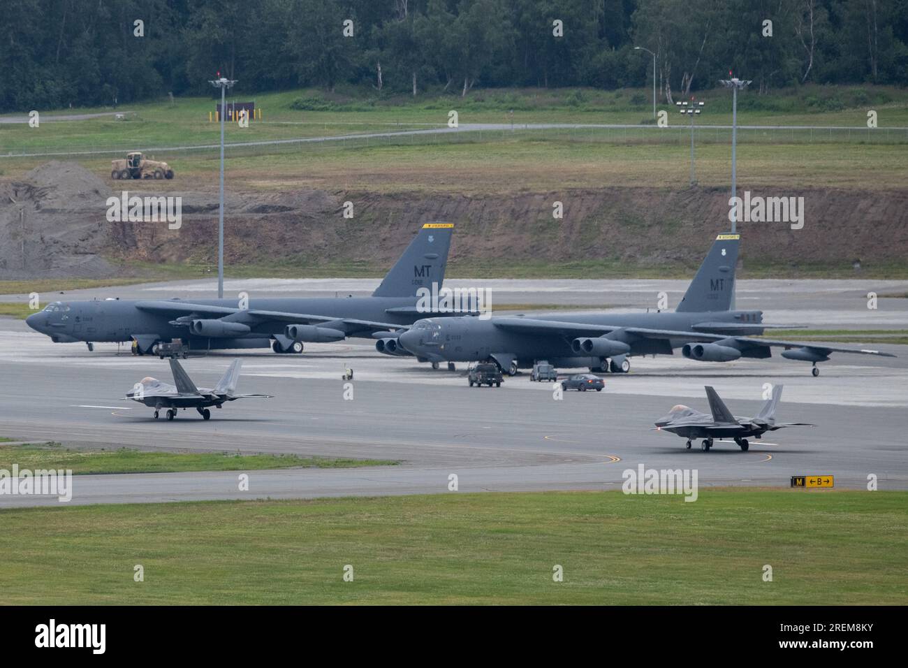 USA Air Force F-22 Raptors, die dem 3. Flügel-Taxi zugewiesen wurden, passieren 5. Bombenflügel B-52 Stratofestungen auf der Joint Base Elmendorf-Richardson, Alaska, 26. Juli 2023. Alaskas geografische Lage macht Alaska zu einer strategischen Energieprojektionsplattform für die Vereinigten Staaten. Alaska ist die nächstgelegene US-amerikanische Lage zum Zentrum der nördlichen Hemisphäre und daher einzigartig näher an vielen nationalen Hauptstädten der Hemisphäre als die meisten Punkte in den Lower 48-Staaten. (USA Air Force Photo von Senior Airman Patrick Sullivan) Stockfoto