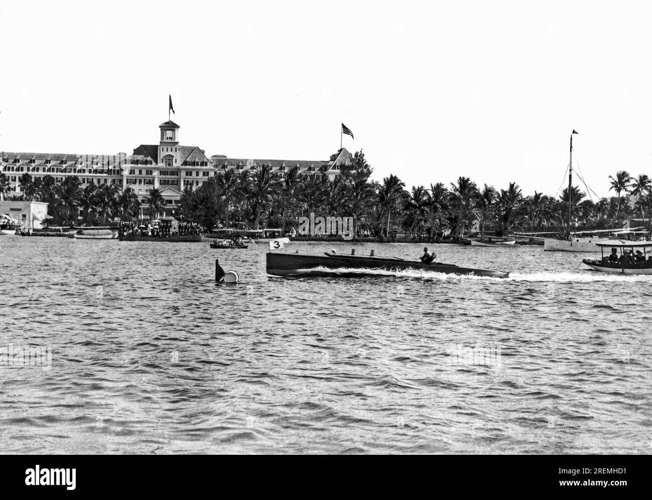 Palm Beach, Florida c 1916 Ein Schnellboot in der Lake Worth Lagune, das am Royal Poinciana Hotel vorbeifährt, wo eine Menge Leute das Bootsrennen beobachten. Stockfoto