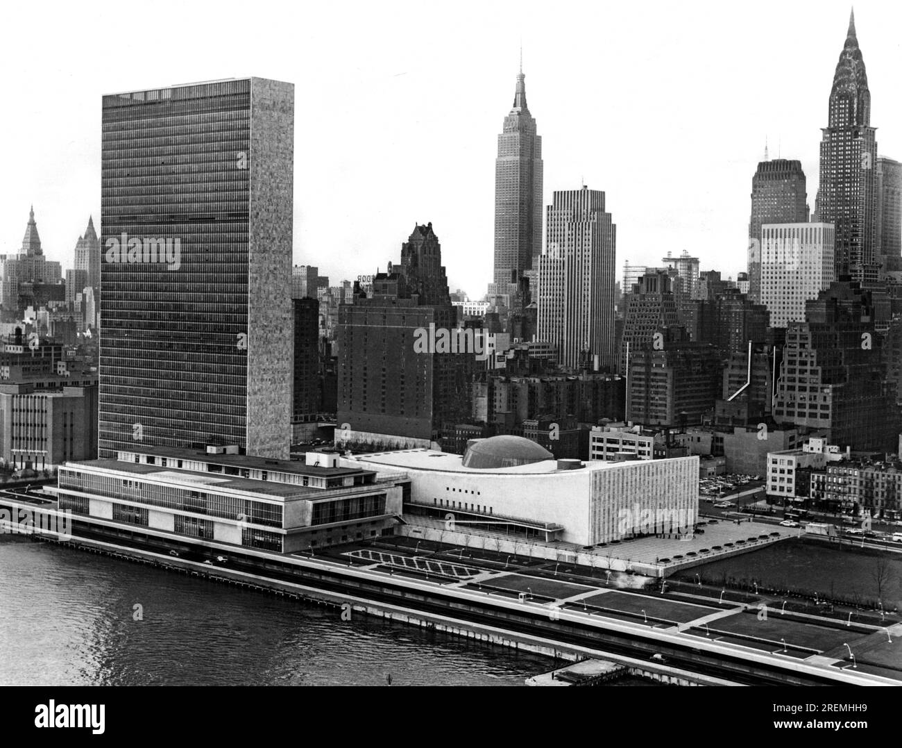 New York, New York: November 1953 Mid-town Manhattan, einschließlich des United Nations Building auf der linken und vorderen Seite, wird in voller Pracht gezeigt mit diesem Foto, das aus einem Flugzeug gemacht wurde, das entlang des East River fliegt. Das Chrysler Building ist das hohe Gebäude auf der rechten Seite, während sich das Empire State Building in der Mitte befindet. Stockfoto